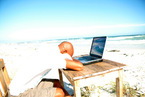 person on beach with laptop
