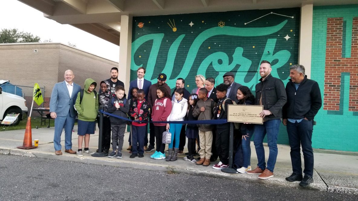 people posing with a check outside of a building