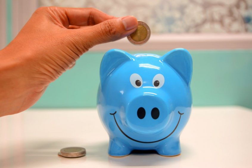 hand putting a coin in a blue piggy bank